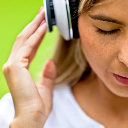 Woman with eyes closed and headphones on taking time to listen to self care audiobooks on xigxag