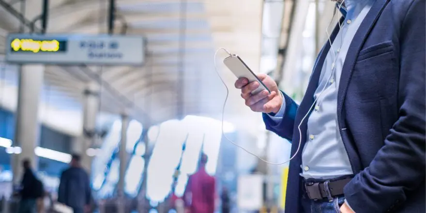 casual business man listening to headphones and looking at smartphone in train station