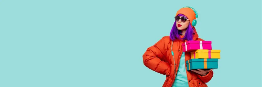 A woman wearing bold colours and headphones carrying brightly coloured gifts