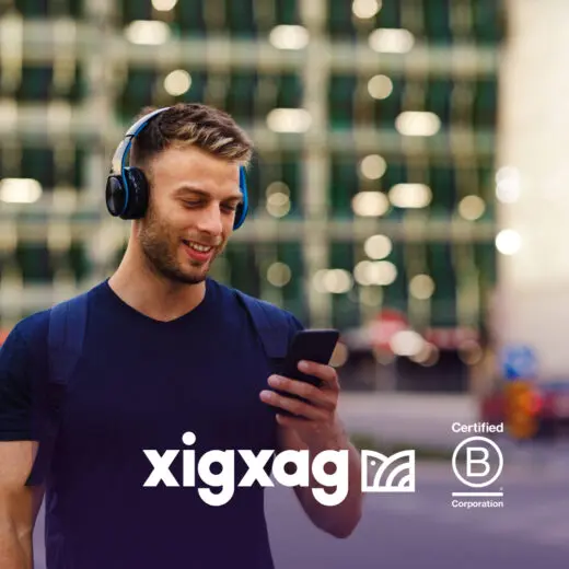 Man with headphones looking at phone and smiling to signal trust in xigxag privacy-first audiobook app