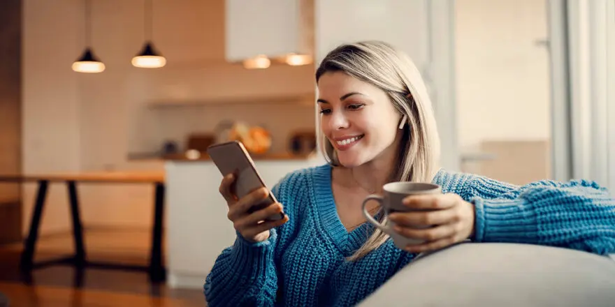 woman relaxing in a modern apartment listening to audiobooks and looking at her smartphone