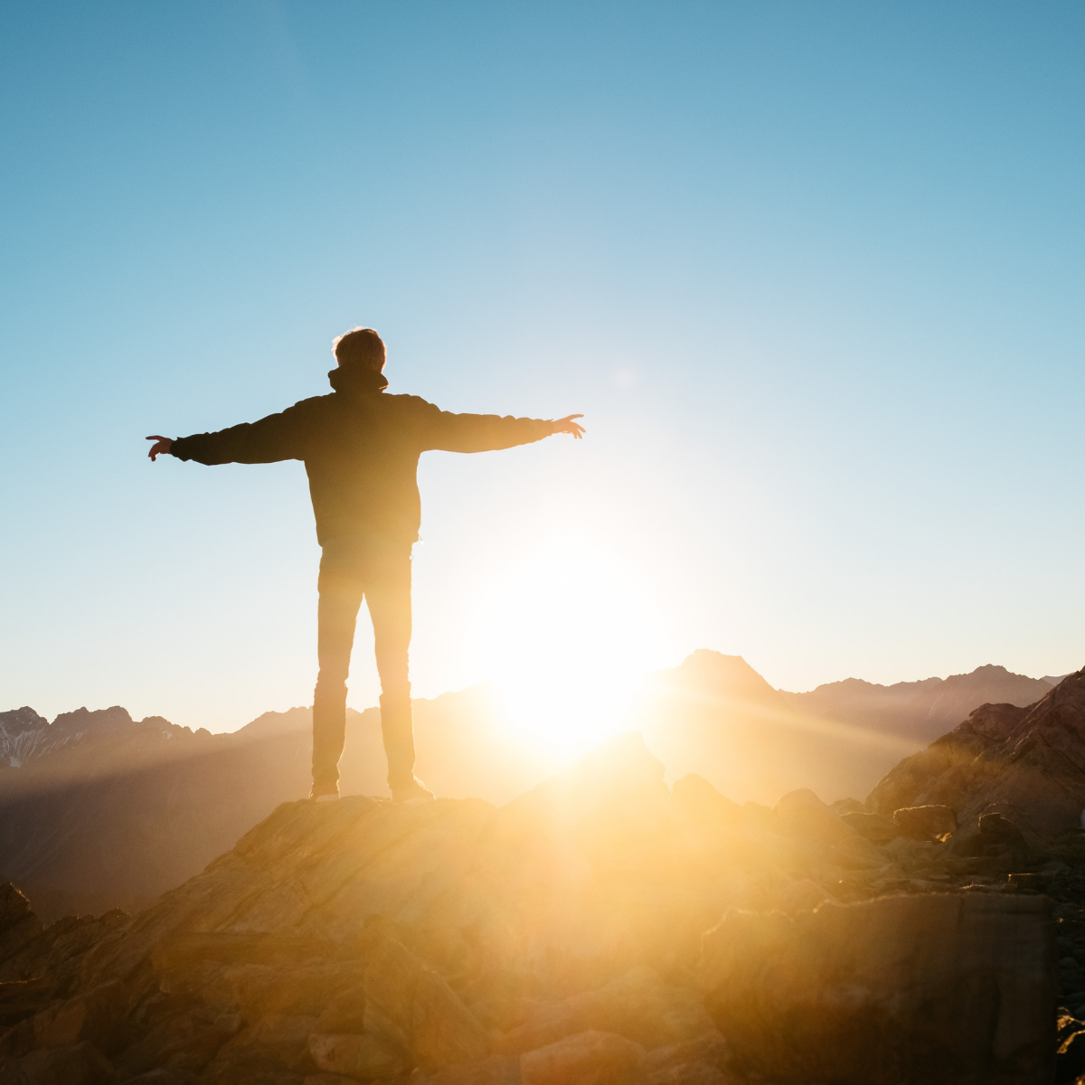 Man with arms outstretched enjoying the sunrise in the mountains with xigxag logo