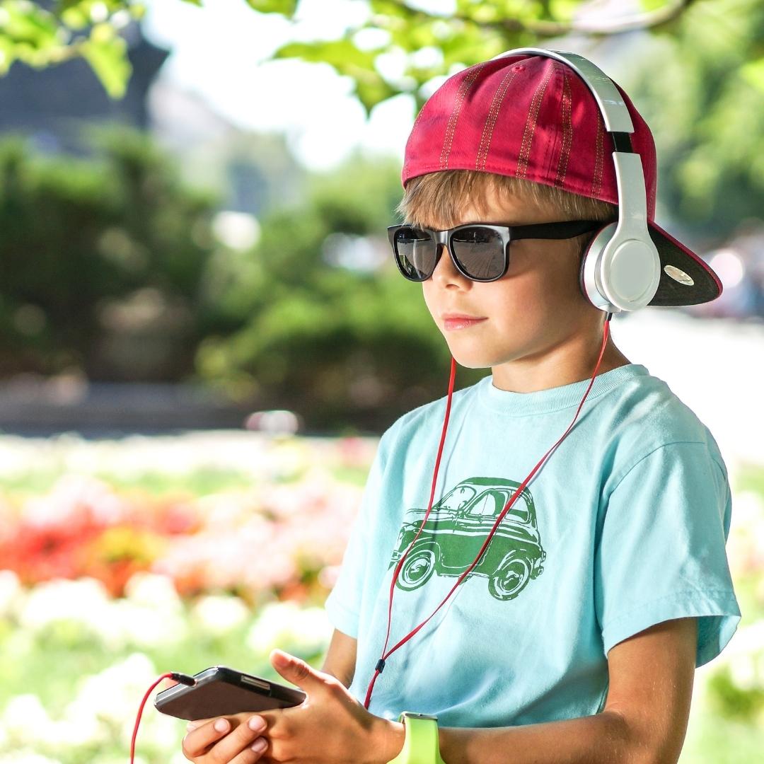 Child listening to audiobooks on his smartphone with sunglasses and headphones